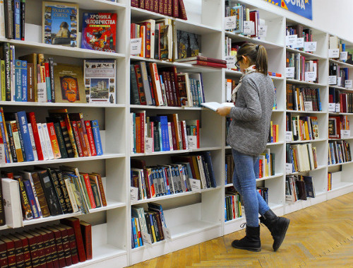 Nuori nainen lukee kirjaa kirjastossa